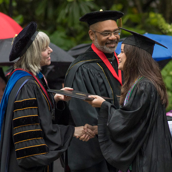 President Hass hands a diploma to a graduating senior