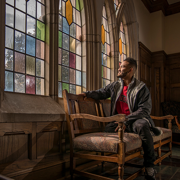 a young African American man looks out a stained glass window