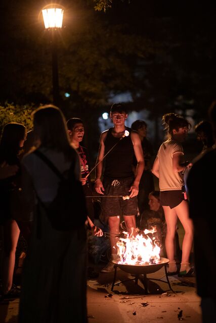 students roast marshmallows over an open fire