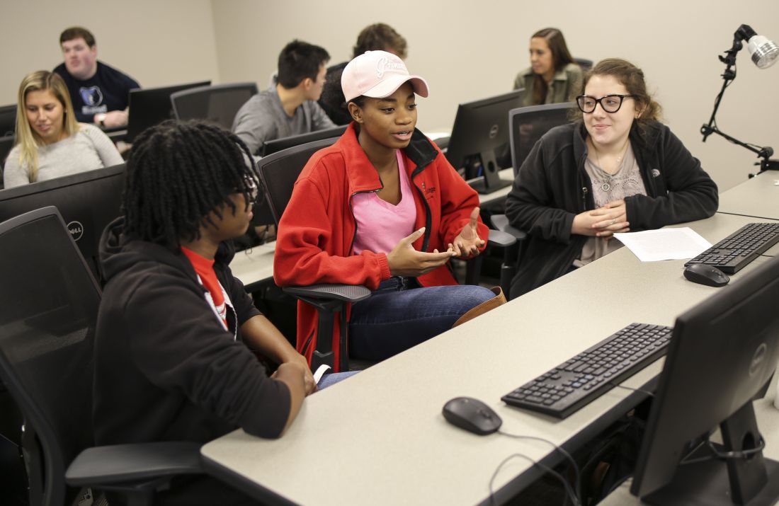 Students discussing in a classroom in front of a computer screen