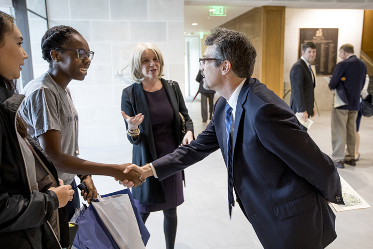 Dr. Larry Hass shakes hands with a student on campus