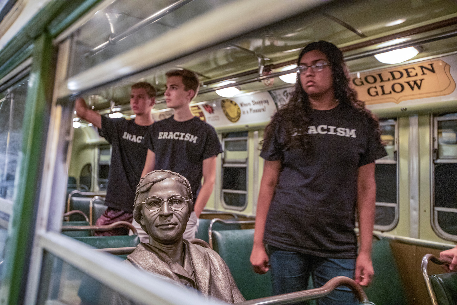 Students stand in a bus with a sculpture of Rosa Parks