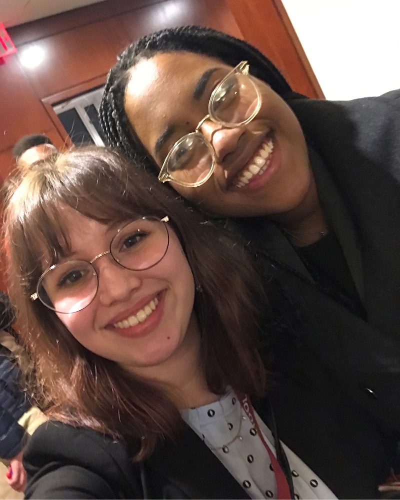 two females stand close together and smile at the camera