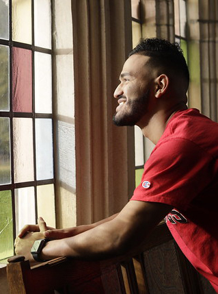 a young African American male looks out a stained glass window