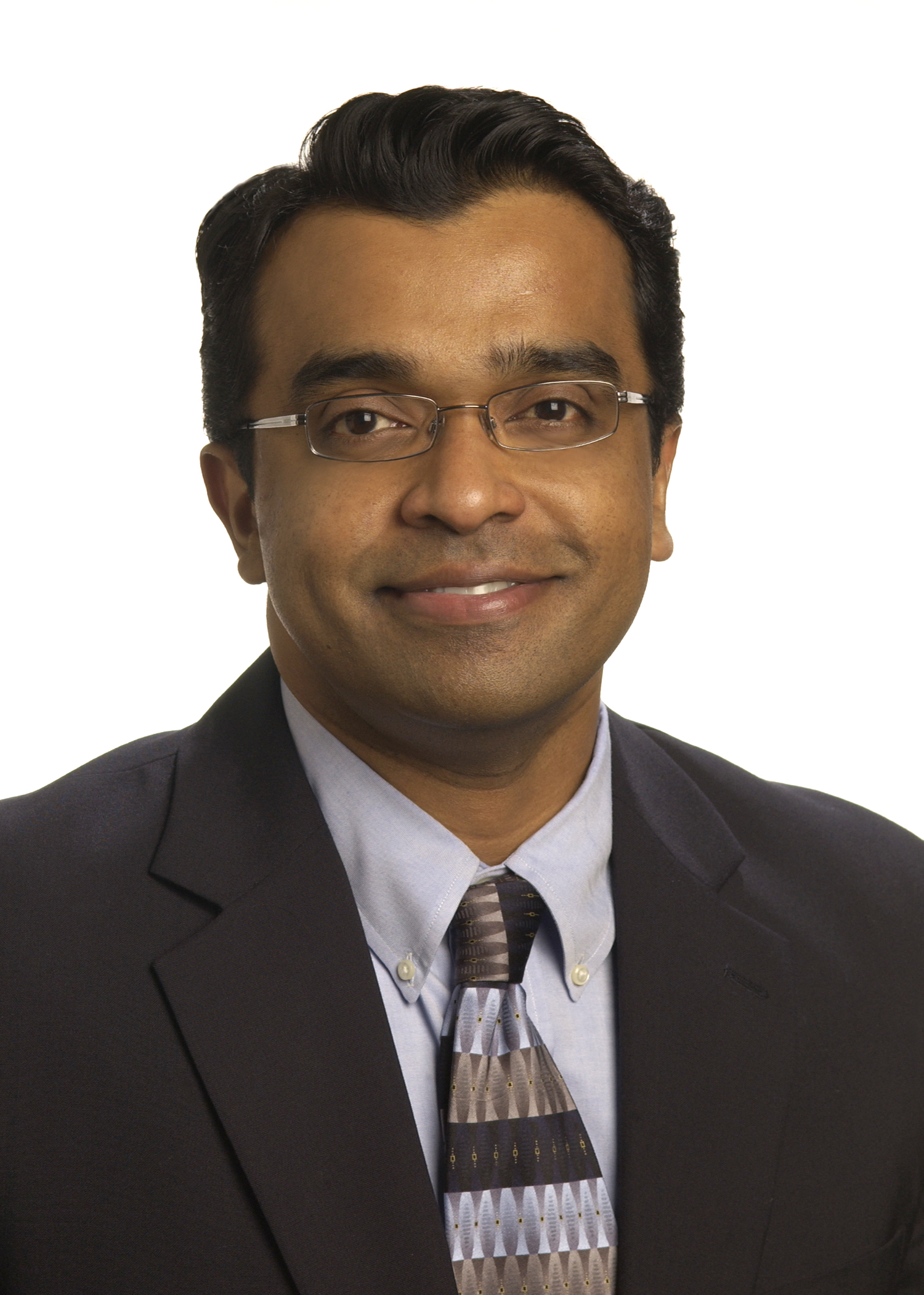 A man in a coat and tie smiling at the camera.