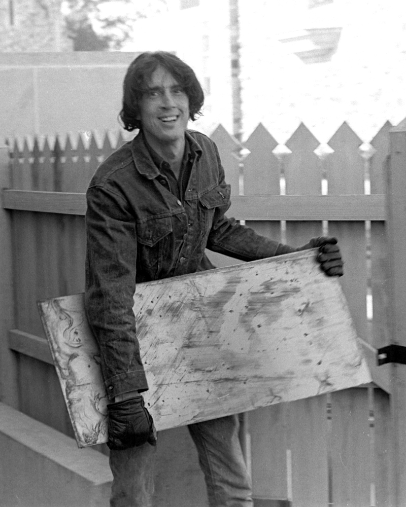 a man with dark hair holds a large stone slab