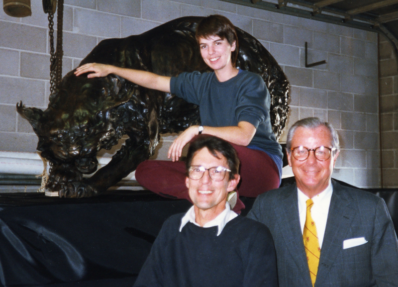 two men and a woman stand by a large statue of a lynx