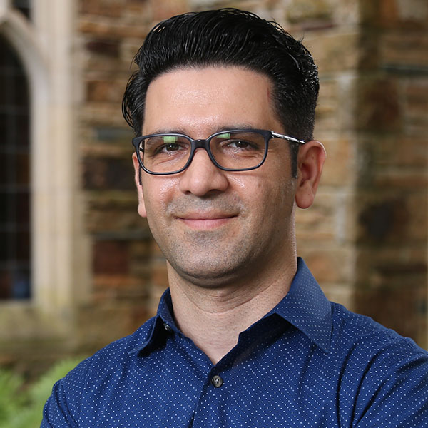 a man with dark hair and glasses in a blue shirt