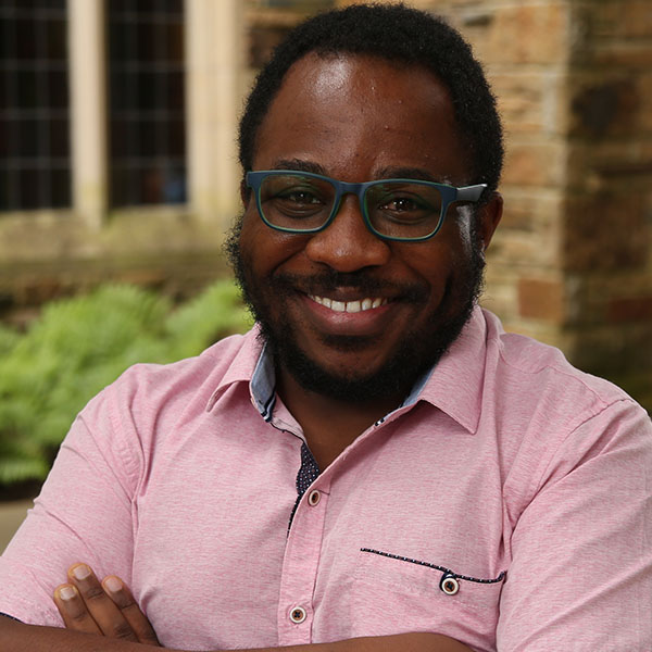 an African American man with glasses in a pink shirt