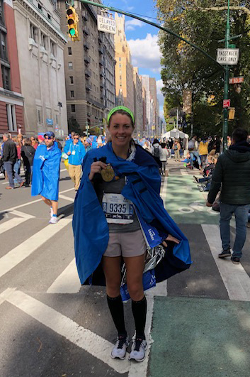 a woman in running gear holds a medal