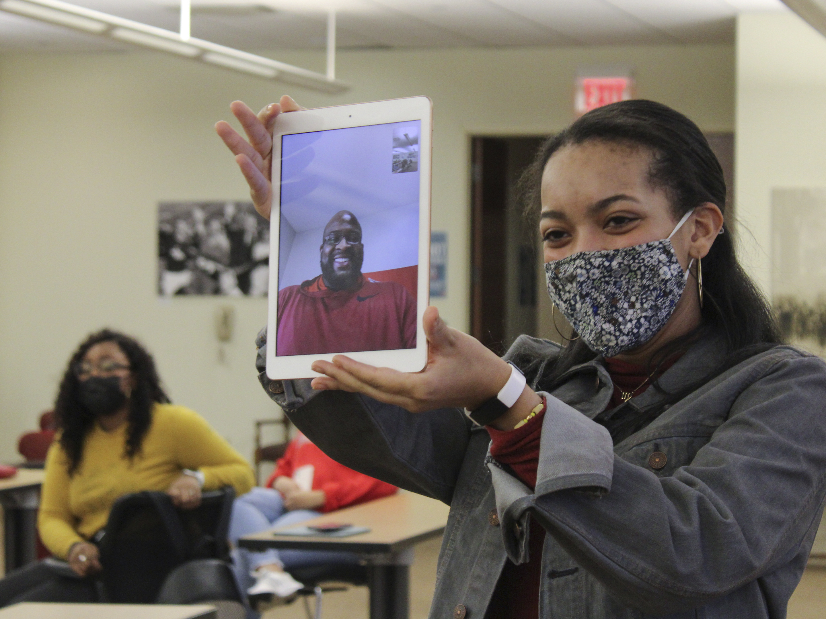 a young woman holds up a screen before an audience