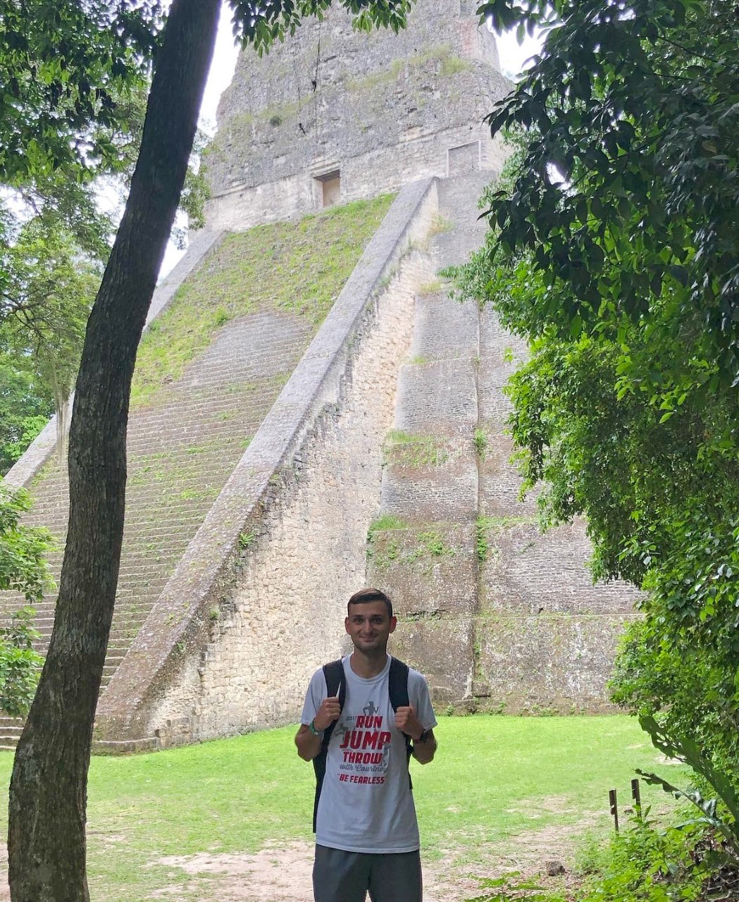  a young man with a backpack in front of a South American pyramid