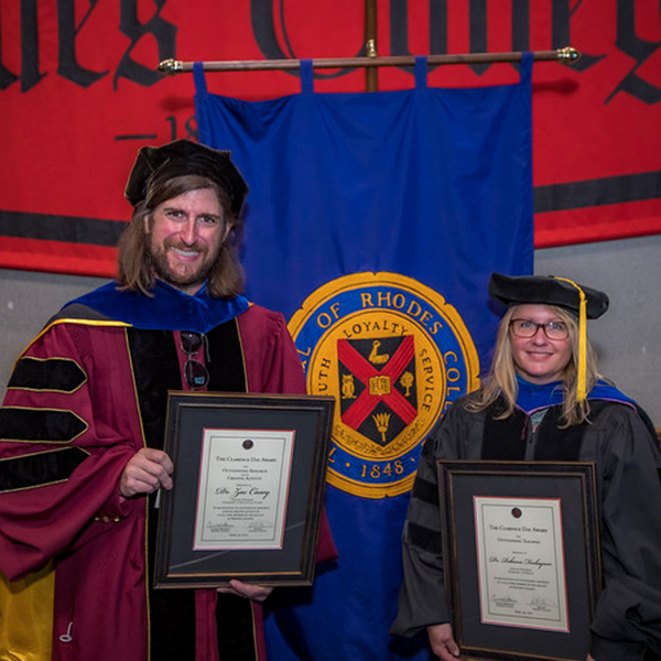 a a man and woman in academic robes pose with awards