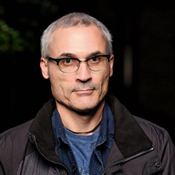a man with gray hair and glasses looks at the camera