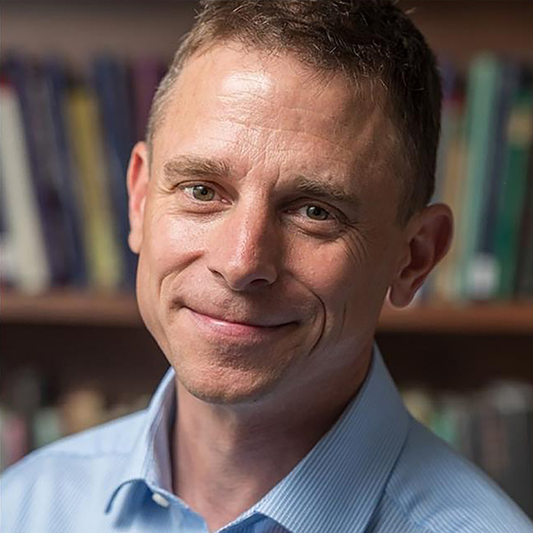 a man with short hair smiles at the camera