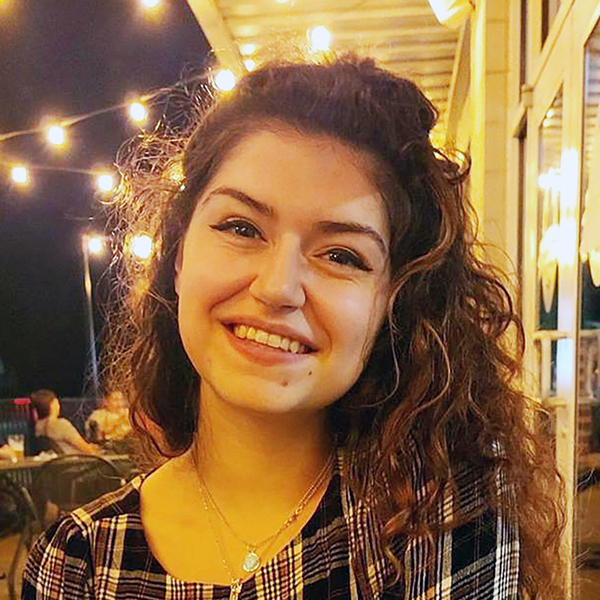 a young woman with long brown hair smiles at the camera