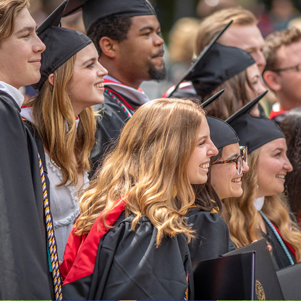 students in graduation regalia pose for a picture