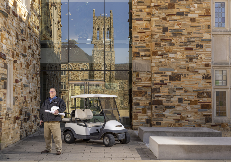 a man with a hard hat stand in front of a large glass wall in a Gothic building