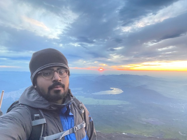 a young man with a mountain in the background