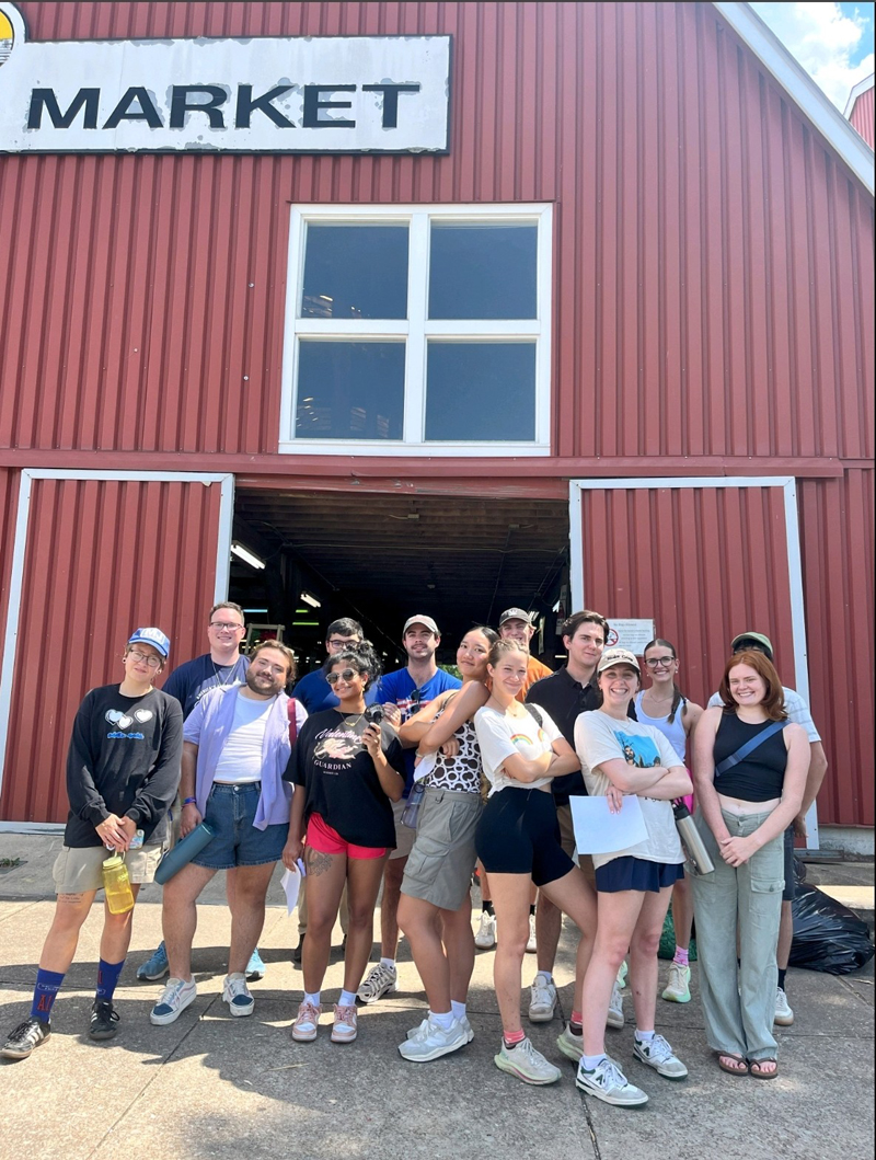 a group of young people pose in front of a barn