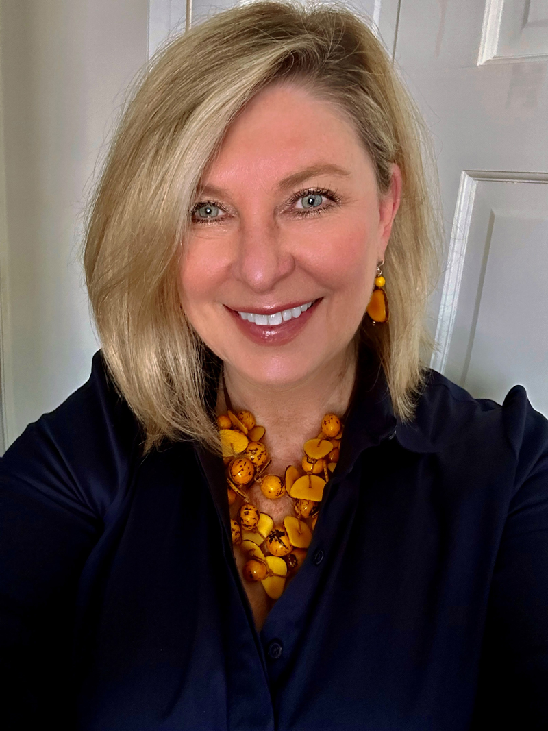 a woman with blonde hair smiles at the camera