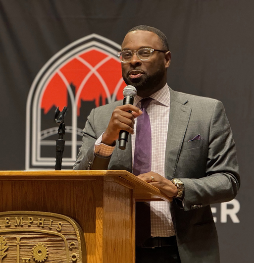 an African American man speaks at a podium