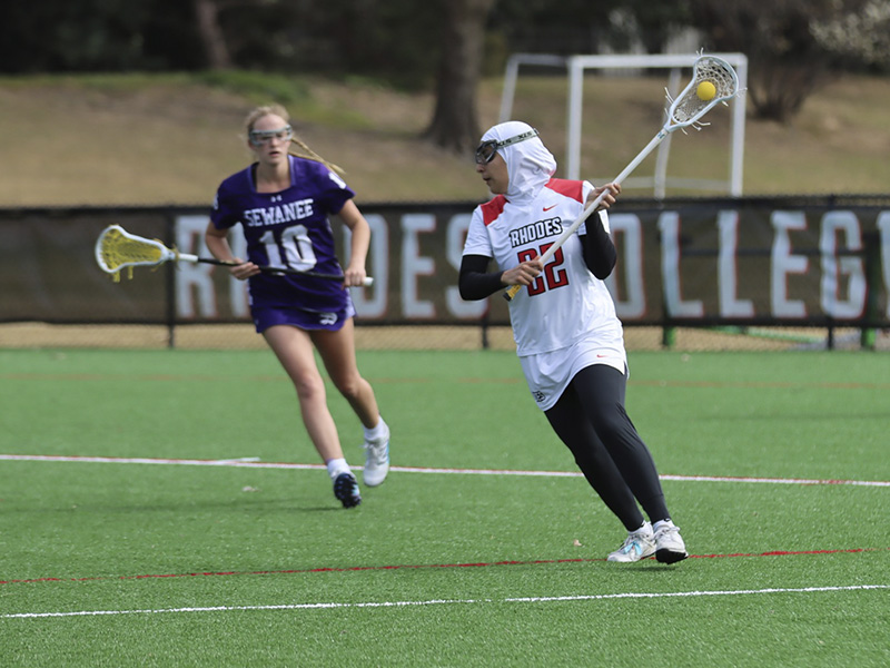 a young woman playing lacrosse and wearing a hijab