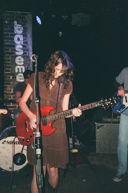 a young woman plays guitar onstage