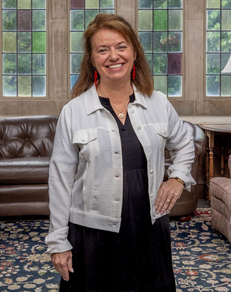 image of Sandi George Tracy standing in front of stained glass windows