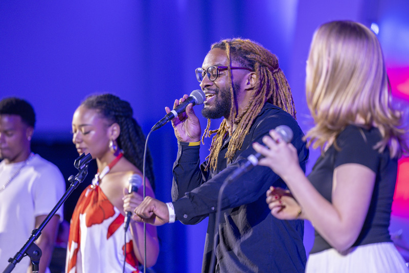 students singing onstage with microphones