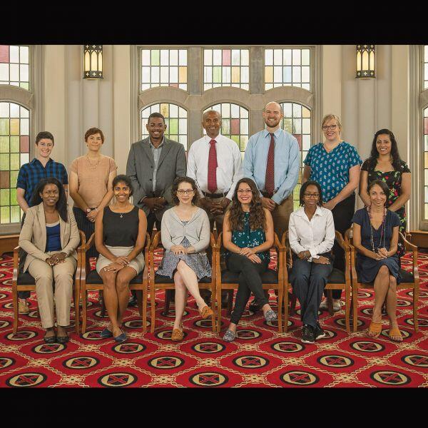 A group of diverse faculty pose in the library.