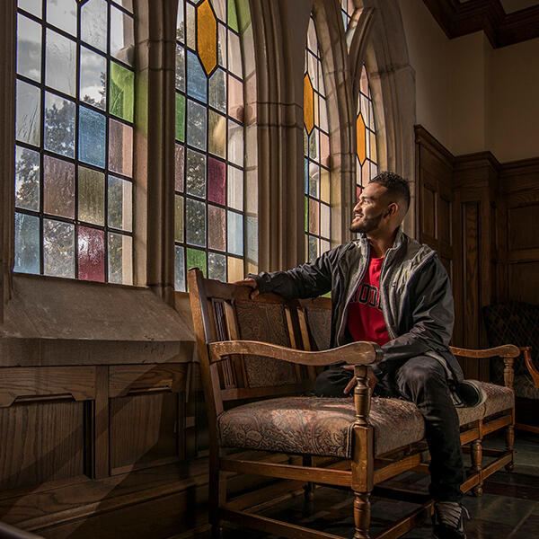 a young African American man looks out a stained glass window