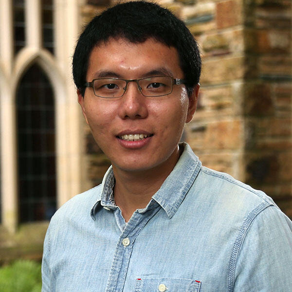 an Asian man with glasses in a blue shirt