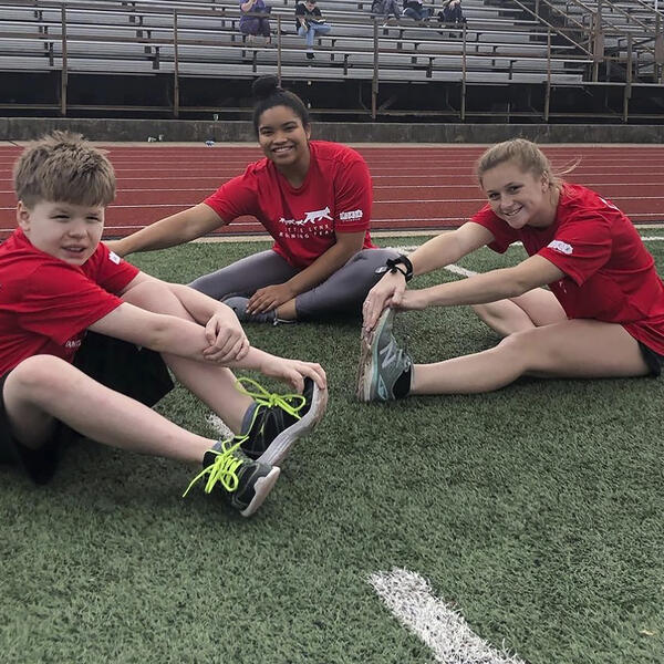 a young boy and college students on a track