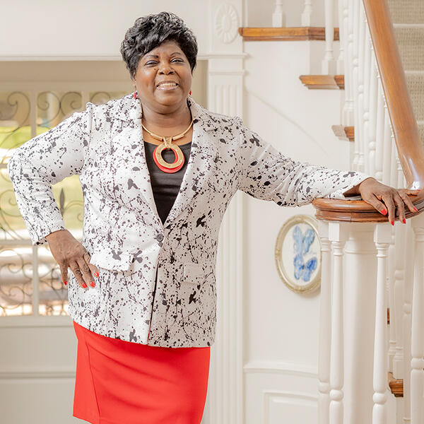 an African American woman stands at a railing, smiling