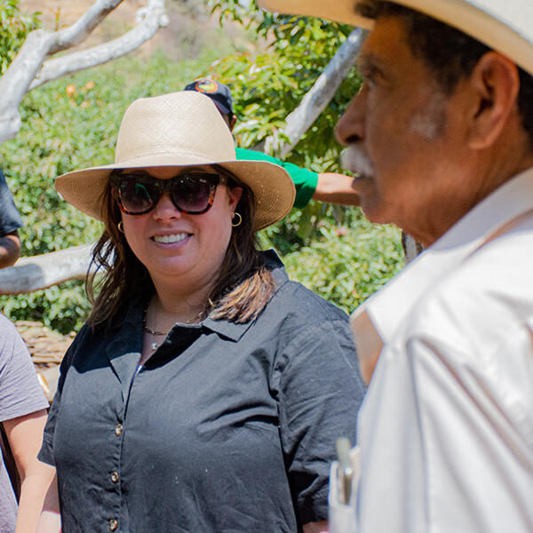 a woman in a hat talks to a Latino man