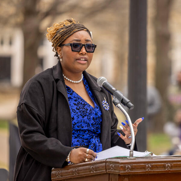 a young African American woman speaks at an outdoor lectern