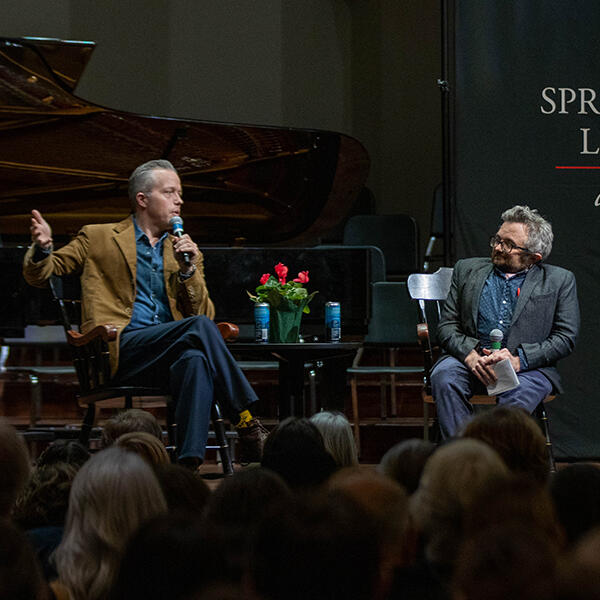 two men talk on a stage