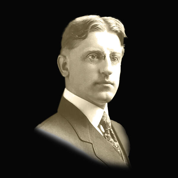 an old-fashioned photo of a man in a suit and glasses