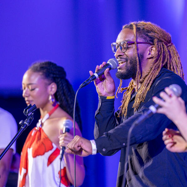 two students sing into microphones