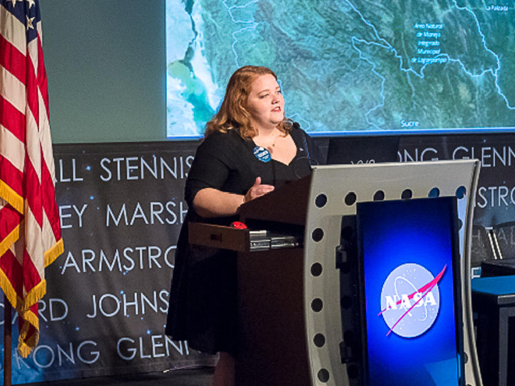 Woman stands at a podium that says NASA