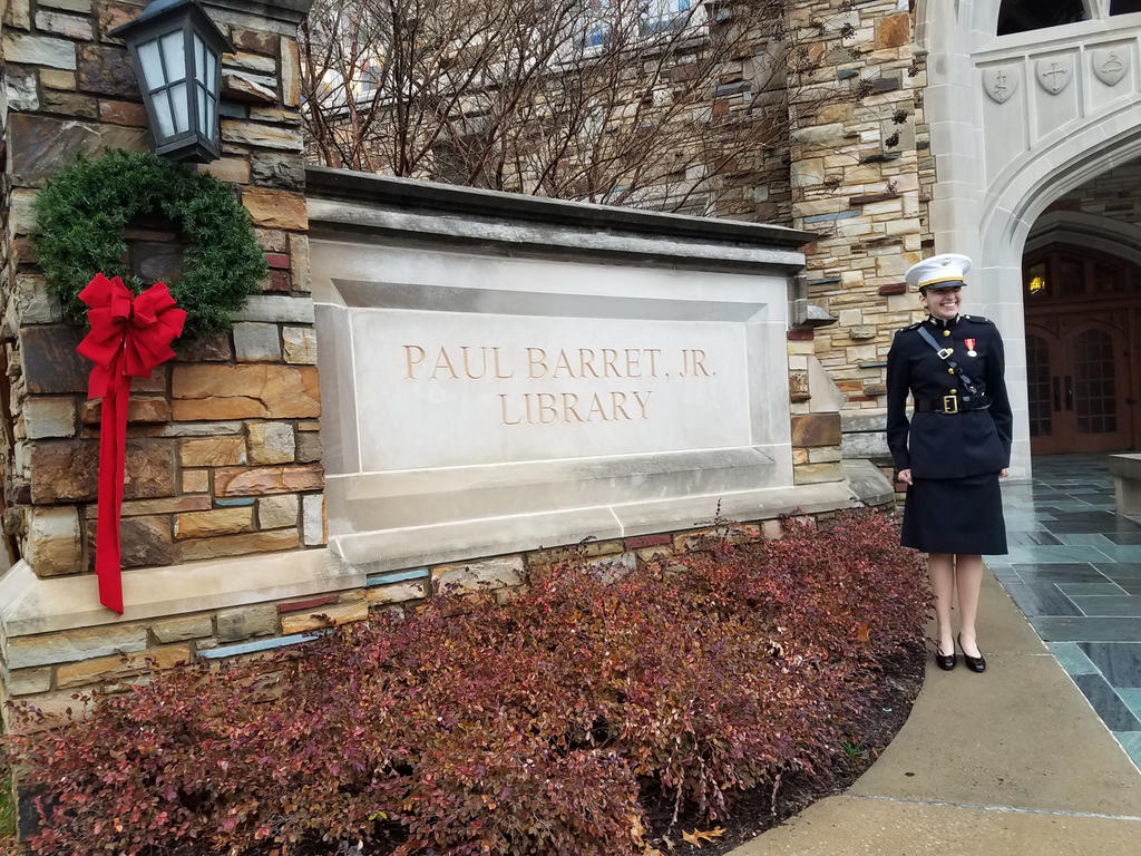 student in a marine uniform standing in front of a campus library sign