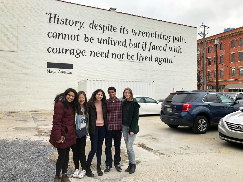 college students standing under quote written on building