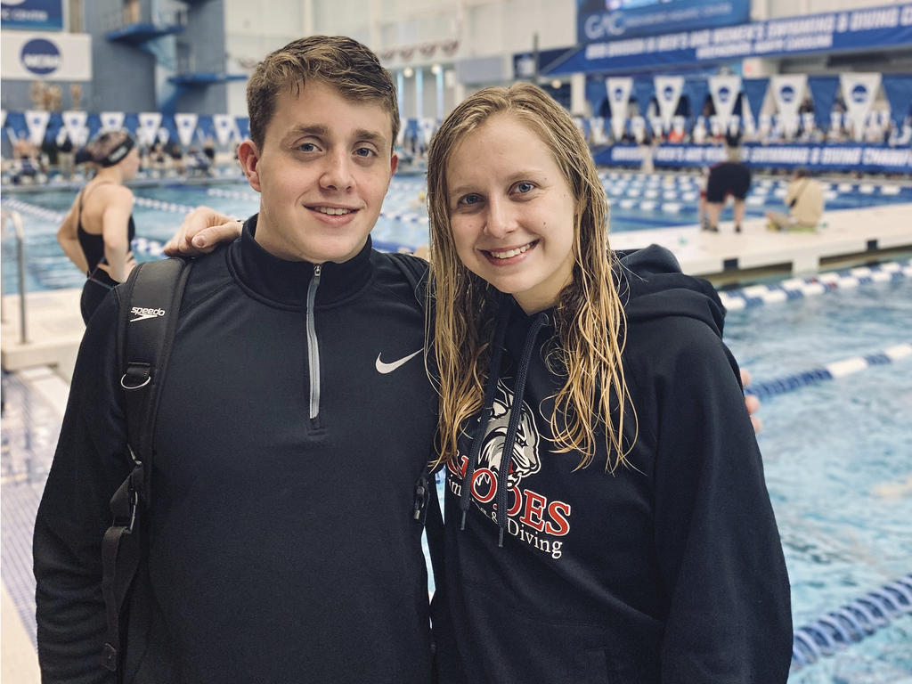 a male and female in front of a pool