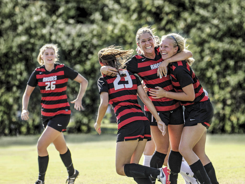 four women in soccer uniforms celebrating on the field