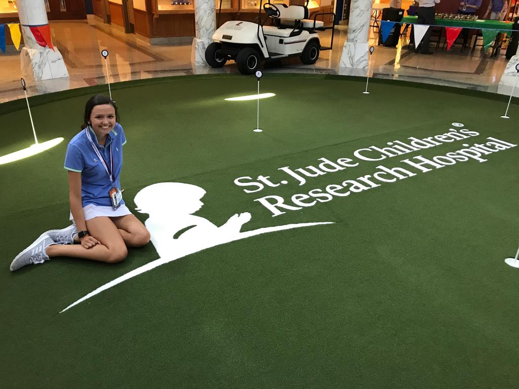Woman sits besides turf with St. Jude logo and name printed on it