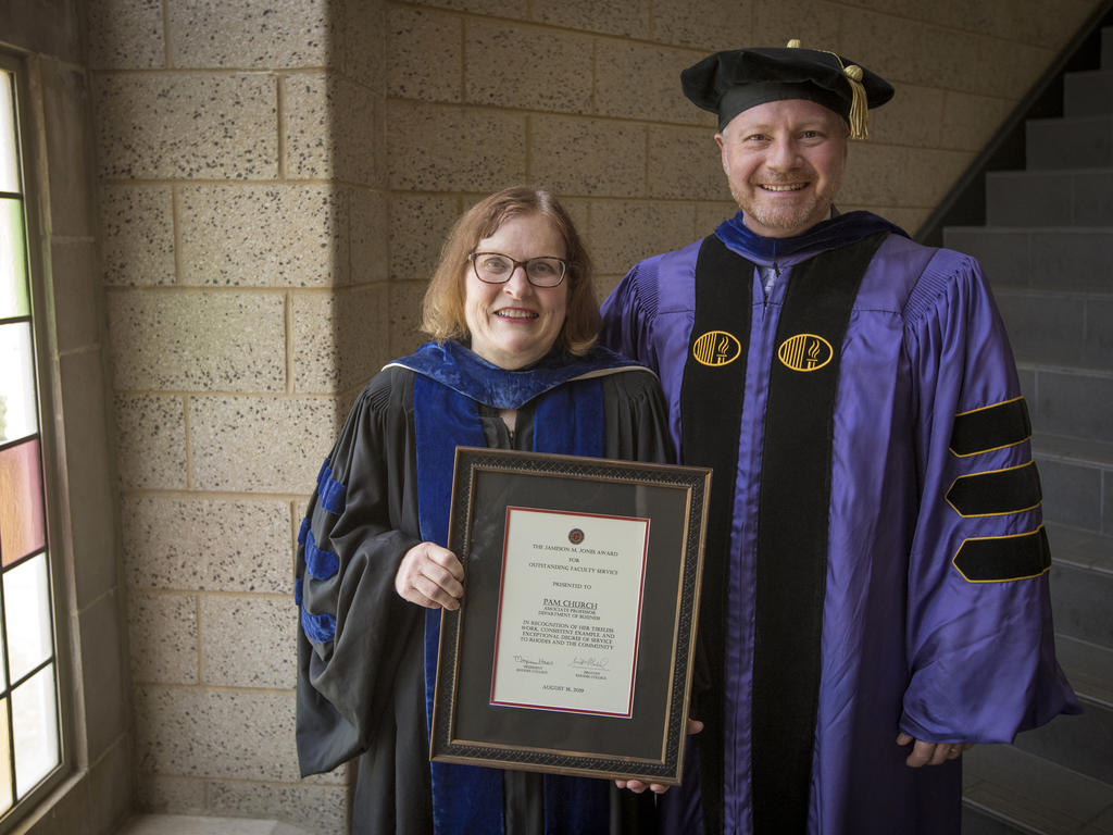 professor, standing next to a college administrator,  holding an award plaque