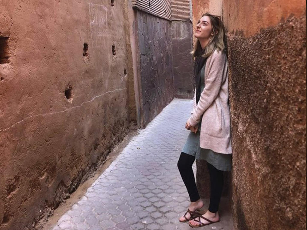 a female leans against a colorful wall 