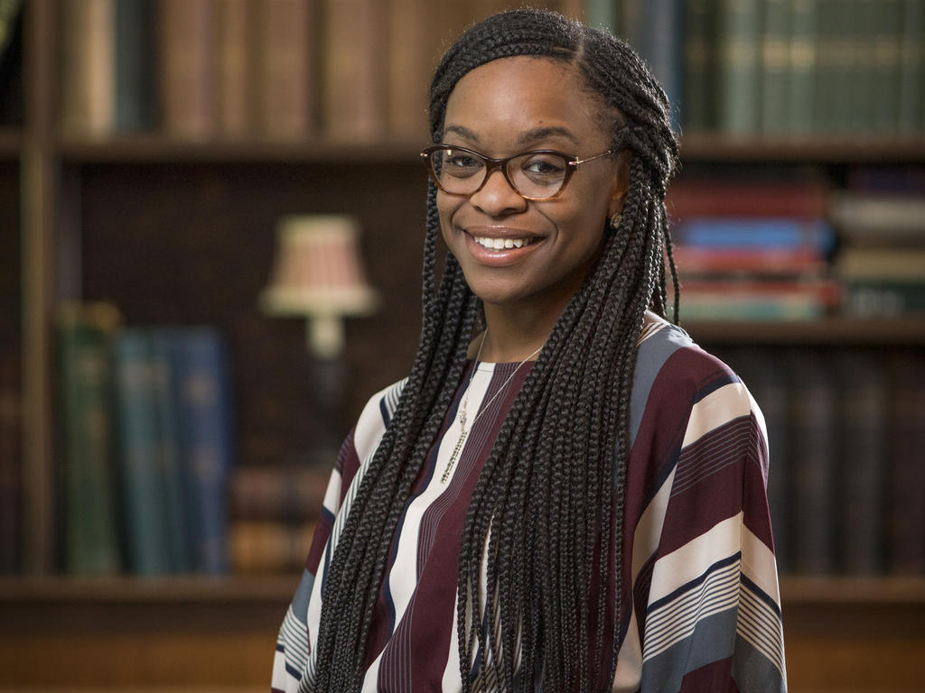 an African American woman with long hair smiles at the camera