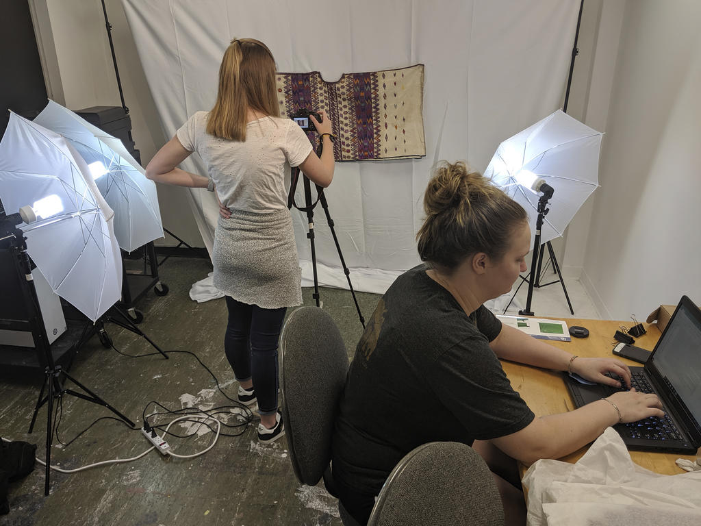 a student photographs an artifact while another student enters the information into a computer